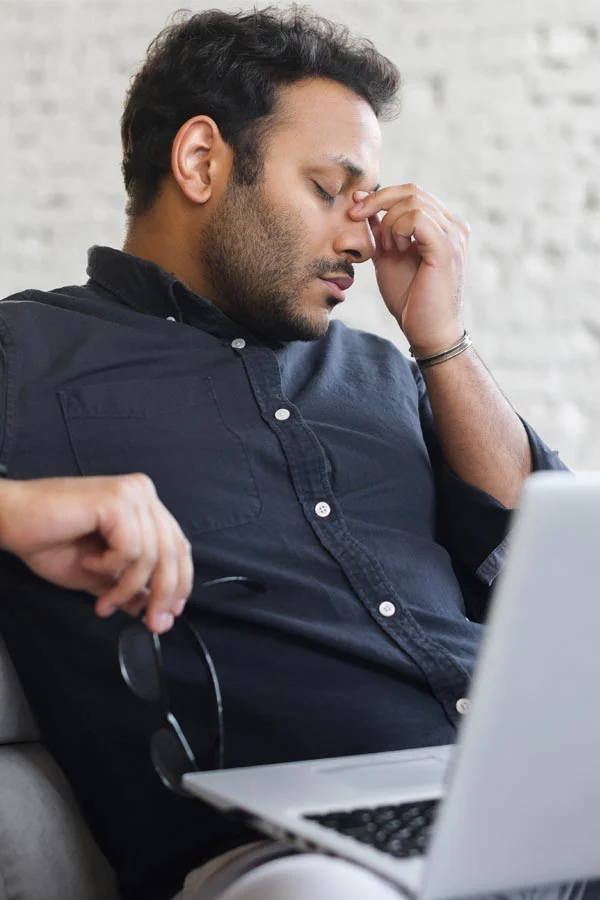 Adrenal-Fatigue-Treatment A middle-aged man with a laptop closing his eyes and rubbing his nose. He needs treatment for Adrenal Fatigue Syndrome from Dr. Donna Diamond in Louisville/Boulder.