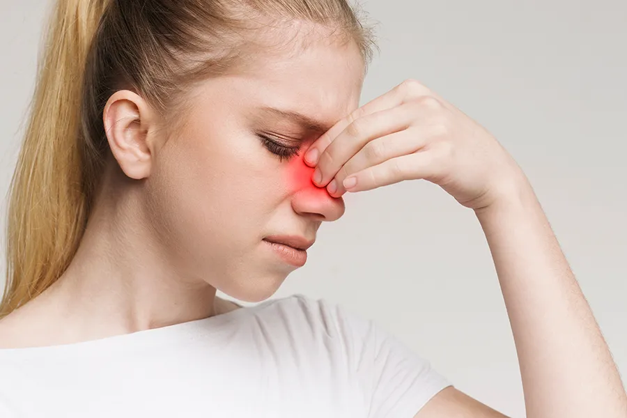Allergic-Rhinitis-Clinic A woman grimaces and rubs the bridge of her nose due to sinus irritation. Get treatment for allergic rhinitis from Dr. Donna Diamond in Louisville/Boulder.