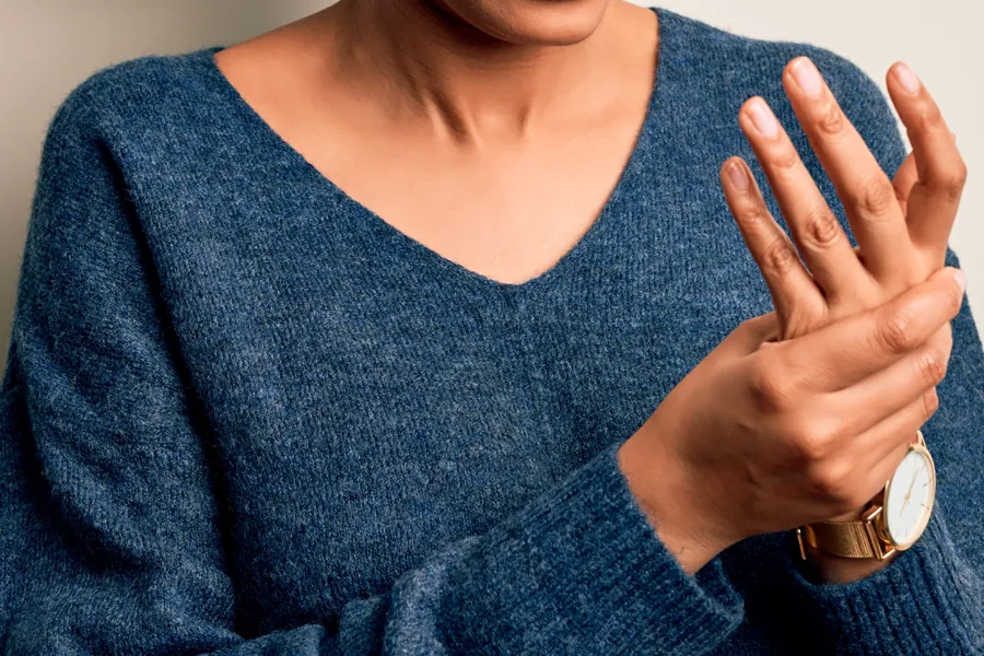 Arthritis-Doctor Close up of a woman in a blue sweater massaging one aching hand with the other. Get help for arthritis from Dr. Donna Diamond in Louisville/Boulder.