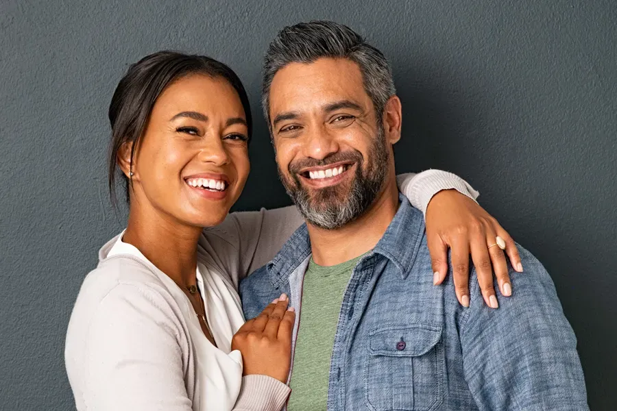 Bioidentical-Hormone-Therapy-Doctor A middle-aged couple with their arms around each other standing against a gray background and smiling, happy with the bioidentical hormone therapy they received from Dr. Donna Diamond in Louisville/Boulder.
