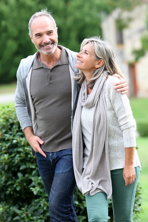 Bioidentical-Hormone-Therapy-Treatment A mature couple in gray toned clothes and jeans walk happily outside, happy with their successful bioidentical hormone treatments from Dr. Donna Diamond in Louisville/Boulder.