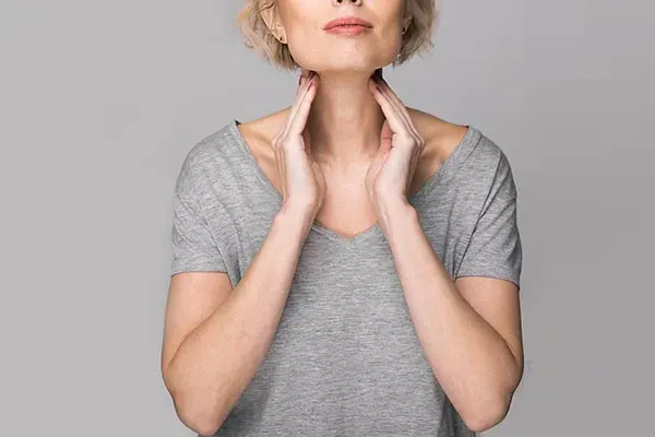 Hashimotos-Thyroiditis-Doctor An older blonde woman in a gray t-shirt holds her hands to her neck checking for signs of thyroid problems. Get help for Hashimoto's Thyroiditis from Dr. Donna Diamond in Louisville/Boulder.