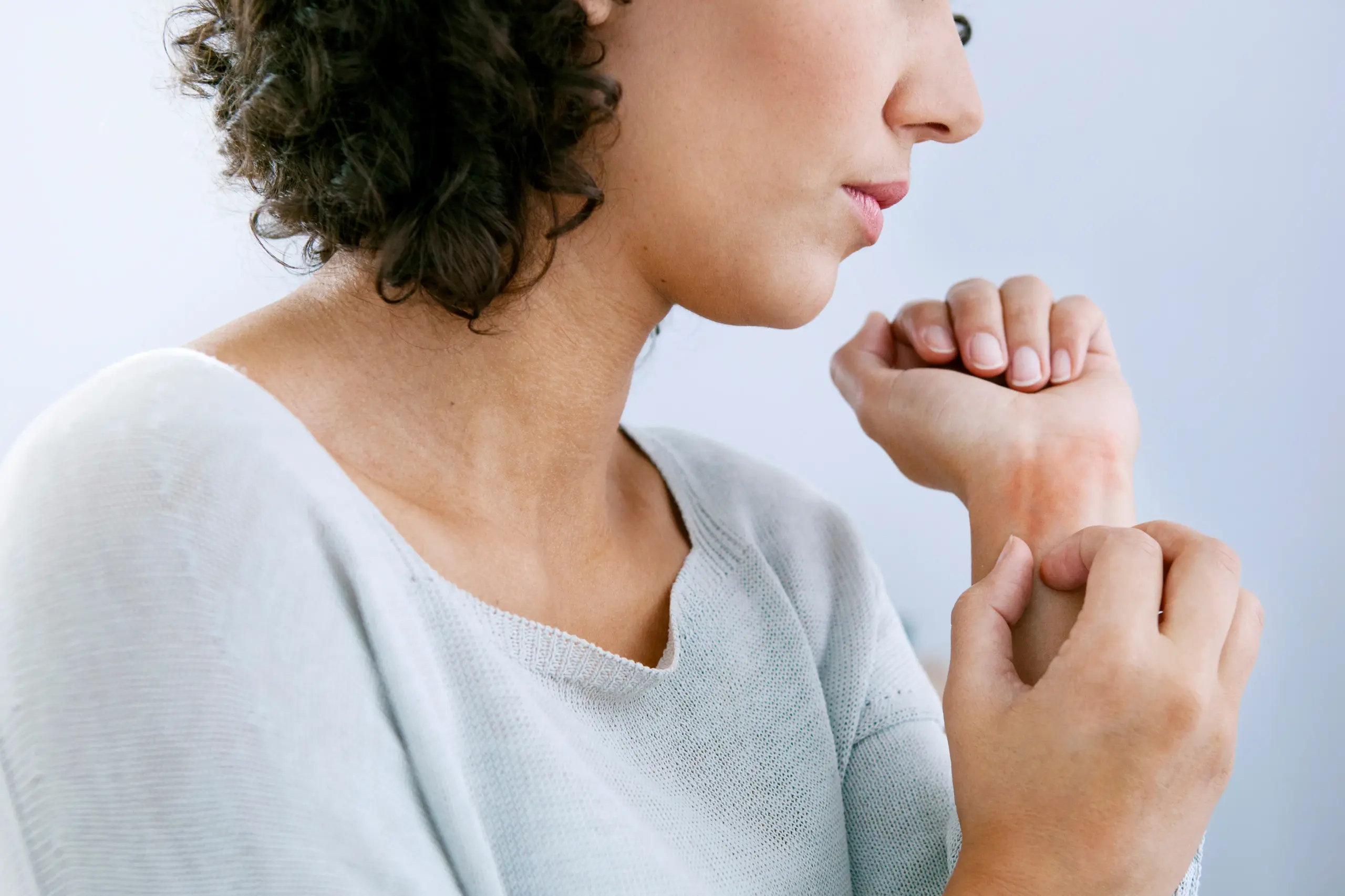 Hives-Doctor A woman with curly brown hair and a light gray shirt scratches her wrist due to hives. Get treatment for hives from Dr. Donna Diamond in Louisville/Boulder.