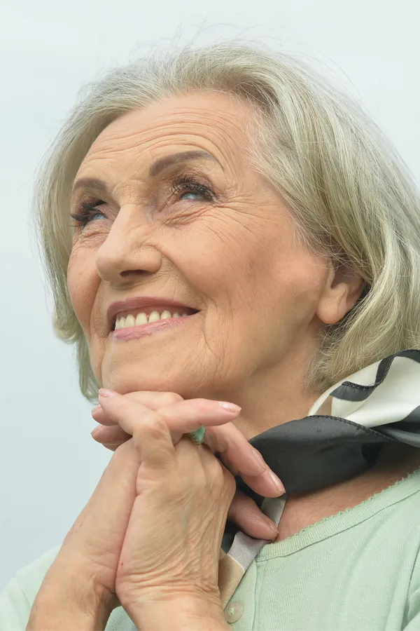 Hot-Flashes-and-Night-Sweats-Treatments An older woman holds her hands together under her chin and looks up at a cool sky smiling. Get treatment for hot flashes and night sweats from Dr. Donna Diamond in Louisville/Boulder.