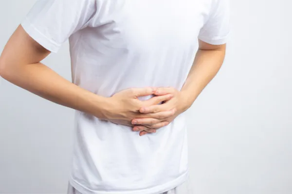 Irritable-Bowel-Syndrome-Clinic A person holding their stomach in visible discomfort against a plain background. Dr. Donna Diamond treats irritable bowel syndrome with functional medicine in Louisville/Boulder.