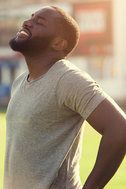 Lean-Muscle-and-Recovery-Treatment A black man in a gray t-shirt and smiles, looking up with closed eyes after a satisfying workout. Get treatment for lean muscle loss and recovery from Dr. Donna Diamond in Louisville/Boulder.