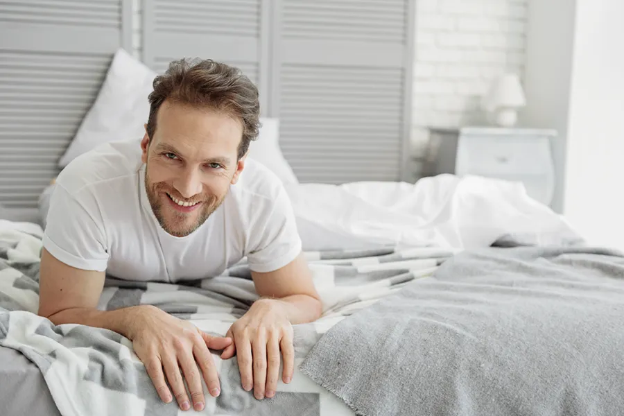 Low-Libido-in-Men-Doctor A dirty-blonde haired man lays on his stomach in bed smiling. Schedule treatment for low libido in men from Dr. Donna Diamond in Louisville/Boulder.
