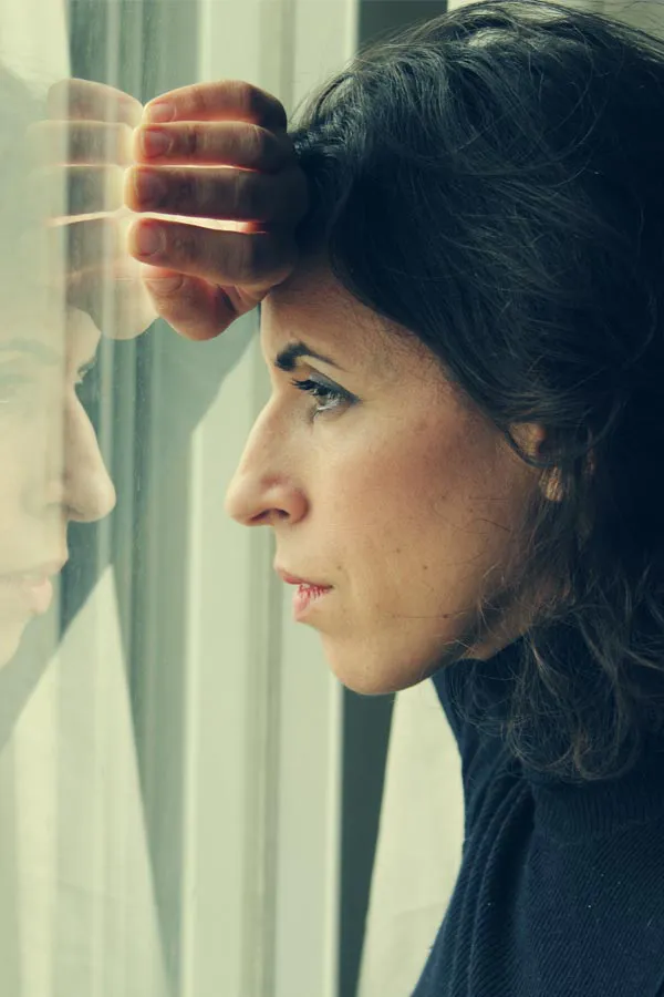 PCOS-Treatment A brunette woman in a thin dark turtleneck looks out the window with a serious expression, suffering from PCOS. Get treatment for Polycistic Ovarian Syndrome/PCOS from Dr. Donna Diamond in Louisville/Boulder.