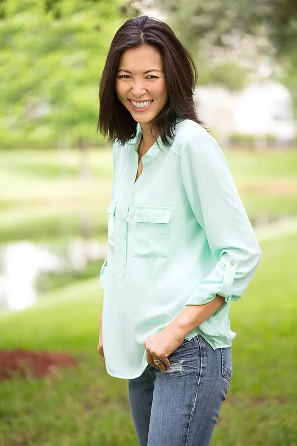 Perimenopause-Treatment A middle-aged brunette woman in a light green button-up shirt stands outside smiling, happy with her perimenopause treatment from Dr. Donna Diamond in Louisville/Boulder.