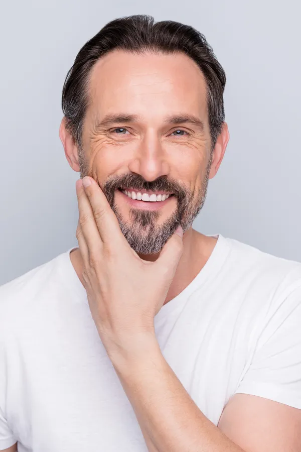 Sjogrens-Syndrome-Treatment Middle-aged man touching his cheek and smiling confidently after finding relief with functional medicine for sjogren's syndrome offered by Dr. Donna Diamond in Louisville/Boulder.