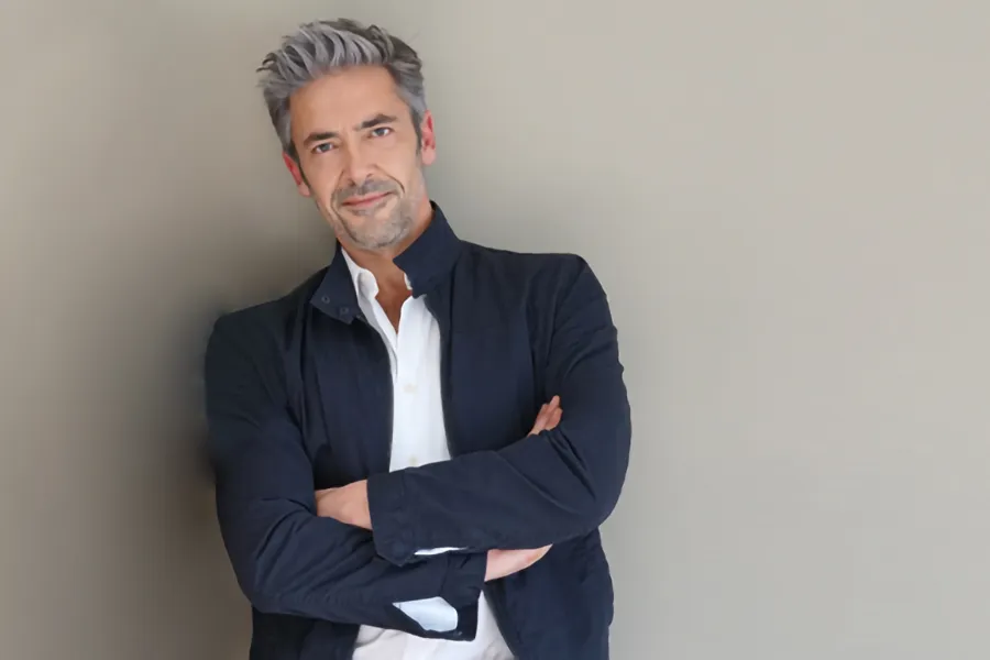 Testosterone-Low-T-Solutionsn-Clinic A middle-aged man in a white shirt and dark blue jacket leans against a gray wall smiling. Get testosterone for Low T from Dr. Donna Diamond in Louisville/Boulder.