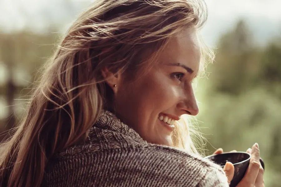 Womens-Health-Exams-Clinic A middle-aged blonde woman in a sweater drinks tea, framed by a forest horizon. Get comprehensive women's health exams from Dr. Donna Diamond in Louisville/Boulder.